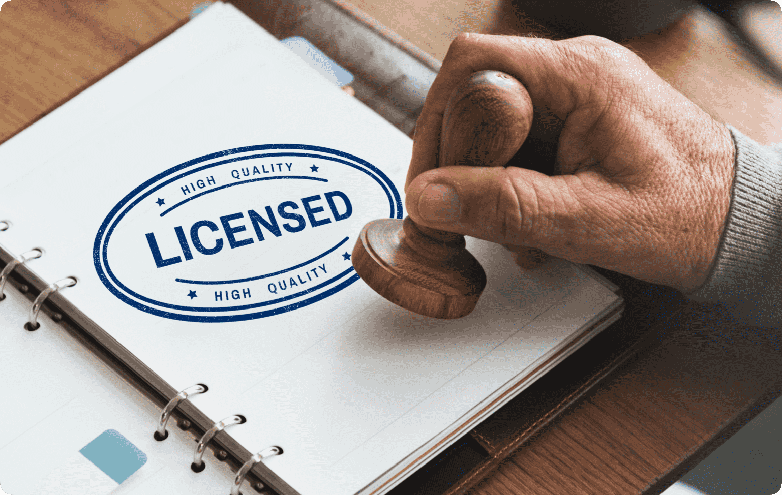 Close-up image of man stamping the words 'high quality, licensed' onto a sheet of paper.