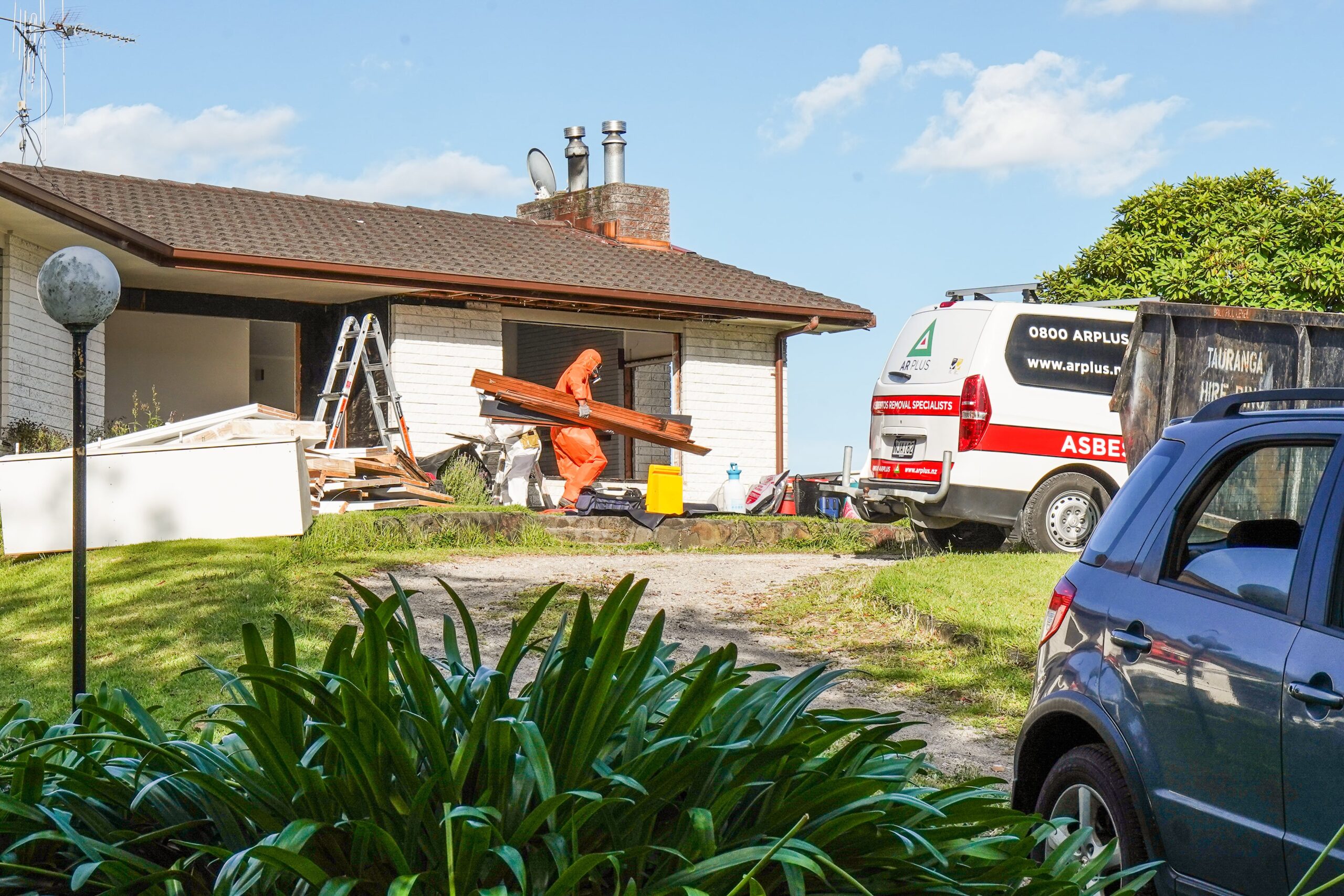 Image of an AR Plus team member carrying asbestos cladding to waste.