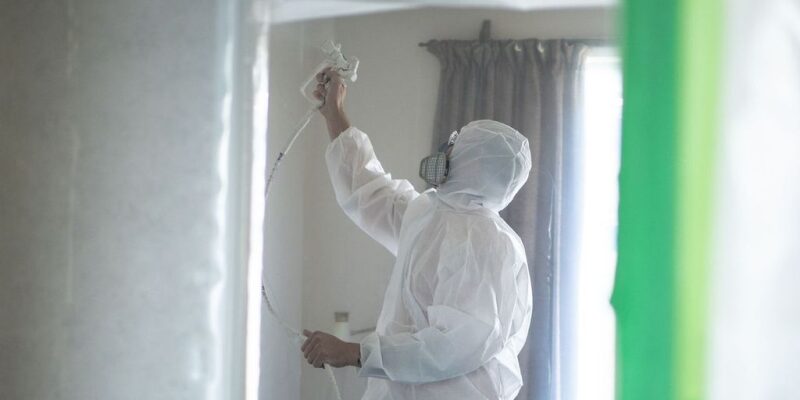 AR Plus team member in PPE applies Tech Coatings IntuGuard to a ceiling.