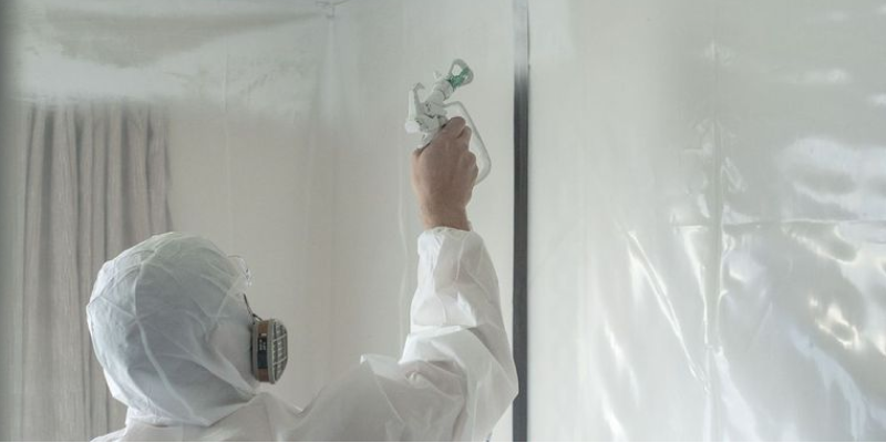 AR Plus team member in PPE applies Tech Coatings IntuGuard to a ceiling.