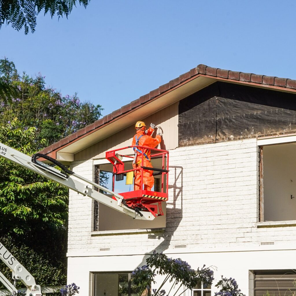 AR Plus professionals in protective suits remove asbestos from a New Zealand property wall.