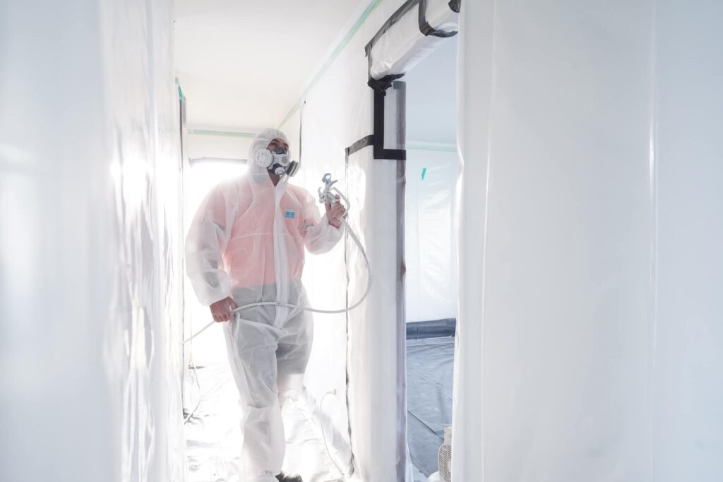 AR Plus team member in PPE working on plastering and painting the interior of a house in Tauranga.